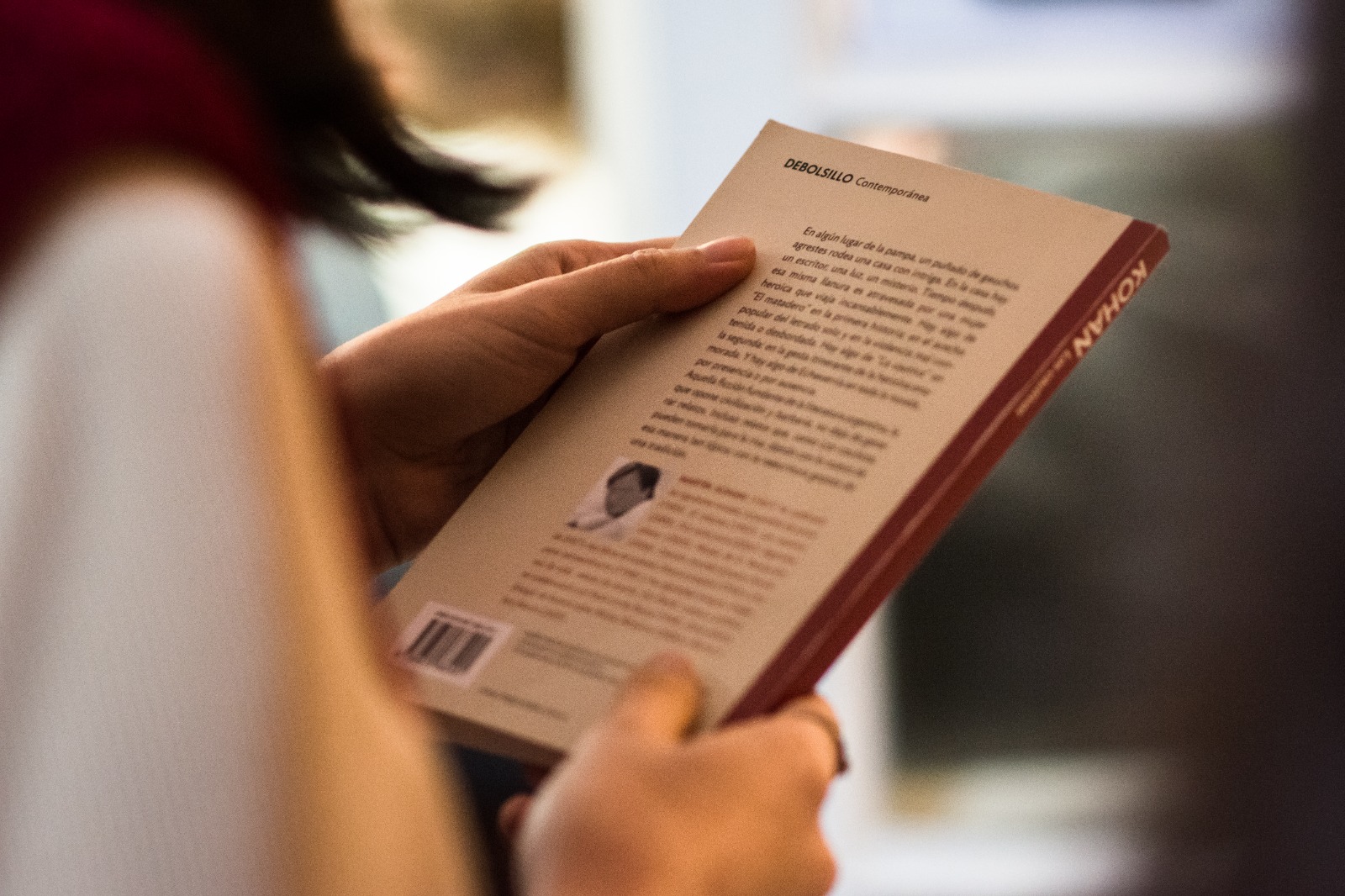 Manos sosteniendo la contraportada de un libro